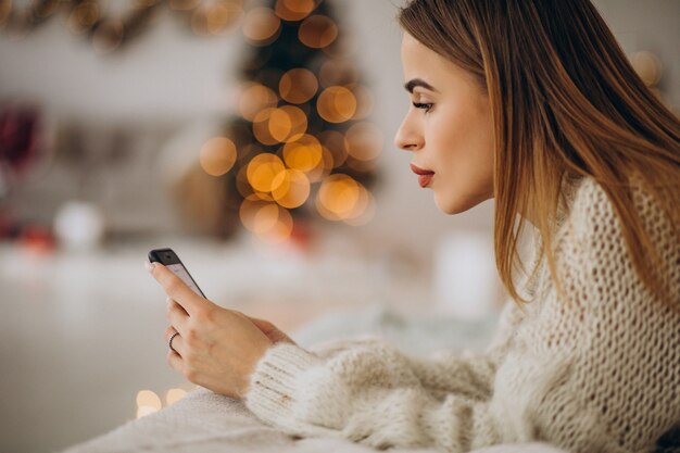 Jonge vrouw met behulp van telefoon op Kerstmis