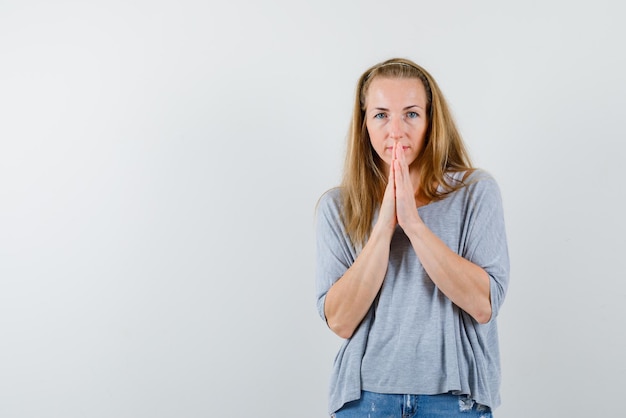 Gratis foto jonge vrouw met biddende handen op witte achtergrond