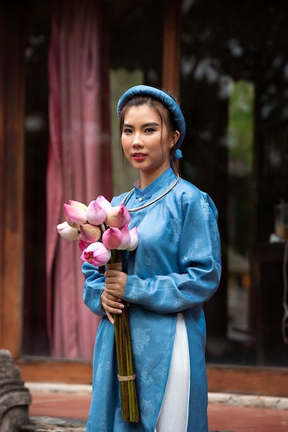 Jonge vrouw met bloemboeket die ao dai-kostuum draagt