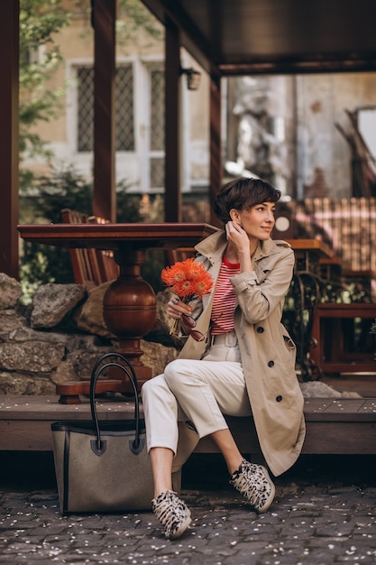Jonge vrouw met bloemen die op straat zit