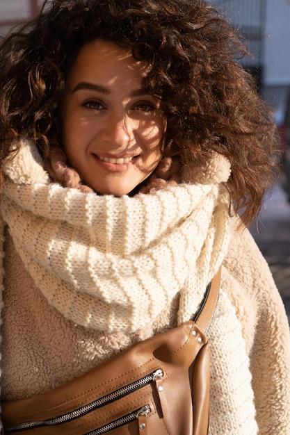 Jonge vrouw met donker krullend haar, warm geklede bontjas, sjaal, wintervorst, zonnige dag op straat in de stad.