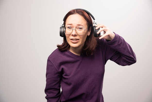 Jonge vrouw met een bril die muziek luistert in een koptelefoon op een wit. Hoge kwaliteit foto