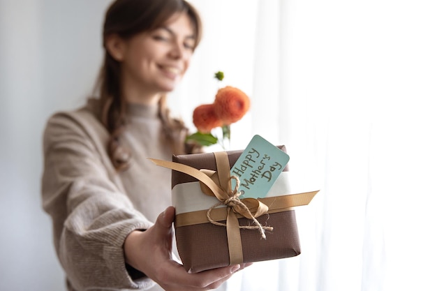 Jonge vrouw met een cadeau voor moederdag en een boeket bloemen in haar handen