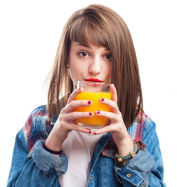 Jonge vrouw met een glas jus d&#39;orange dicht bij haar lippen