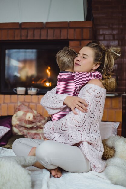 jonge vrouw met een kind. Moeder en zoon zijn aan het plassen, plezier maken bij de open haard.