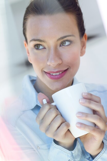 Jonge vrouw met een koffie in de keuken