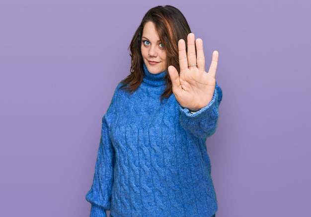 Jonge vrouw met een maatje meer die vrijetijdskleding draagt en stopt met zingen met de handpalm waarschuwende uitdrukking met een negatief en serieus gebaar op het gezicht