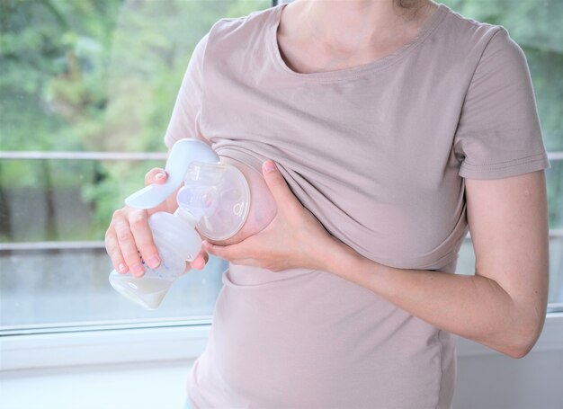 Jonge vrouw met een machine voor het uitdrukken van moedermelk. concept borstvoeding. borstkolf close-up