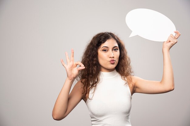 Jonge vrouw met een ok gebaar in witte blouse. Hoge kwaliteit foto