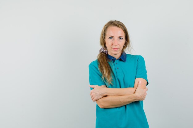 Jonge vrouw met gekruiste armen in t-shirt en op zoek zelfverzekerd