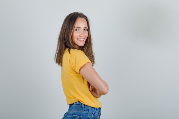 Jonge vrouw met gekruiste armen in t-shirt, korte broek en op zoek vrolijk