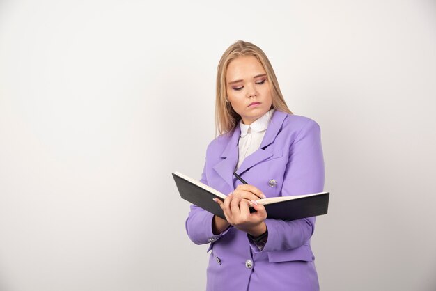 Jonge vrouw met geopende tablet op witte muur.