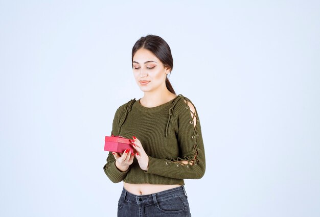 Jonge vrouw met geschenkdoos op witte achtergrond.