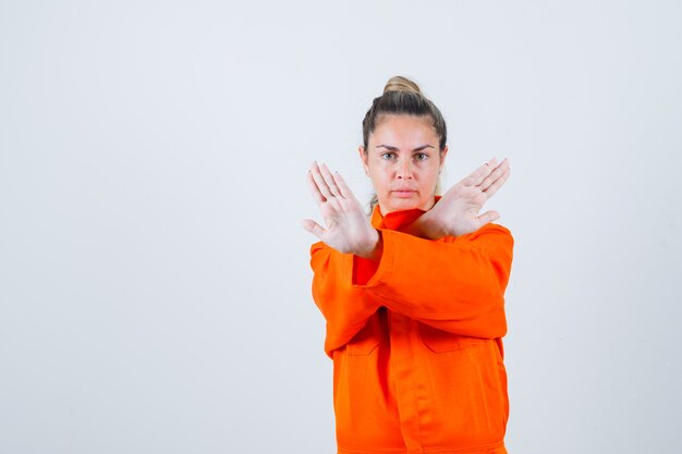 Jonge vrouw met gesloten gebaar in uniform werknemer en op zoek aandachtig. vooraanzicht.