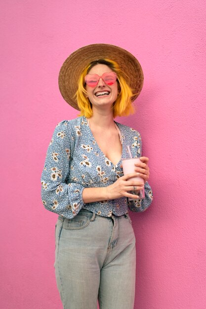 Jonge vrouw met geverfd haar in de buurt van roze muur