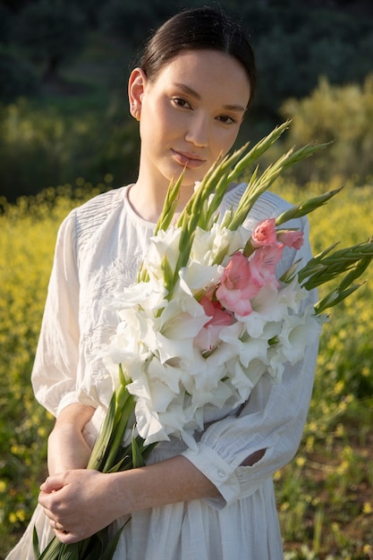 Jonge vrouw met gladiolen in de natuur