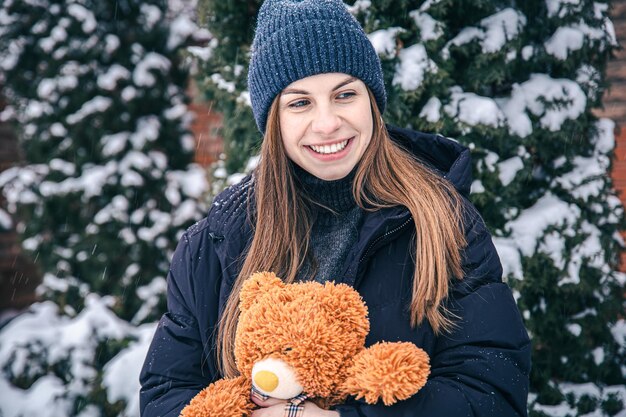 Jonge vrouw met haar favoriete teddybeer in haar armen in de winter