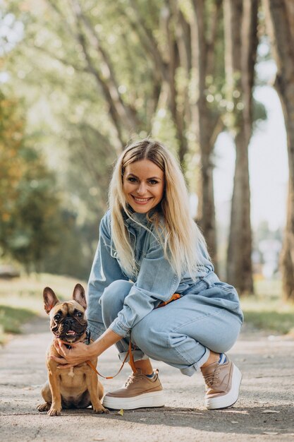 Jonge vrouw met haar huisdier Franse bulldog in park