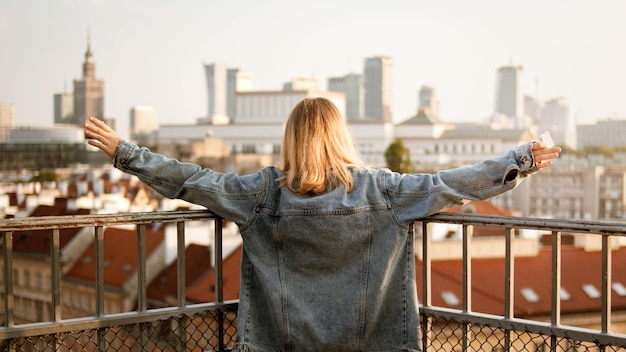 Gratis foto jonge vrouw met haar open armen en de stadsgebouwen