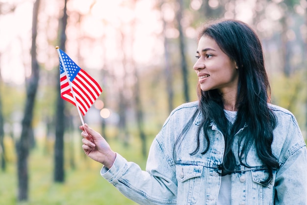 Jonge vrouw met kleine Amerikaanse vlag buitenshuis