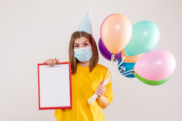 jonge vrouw met kleurrijke ballonnen en opmerking in masker op wit