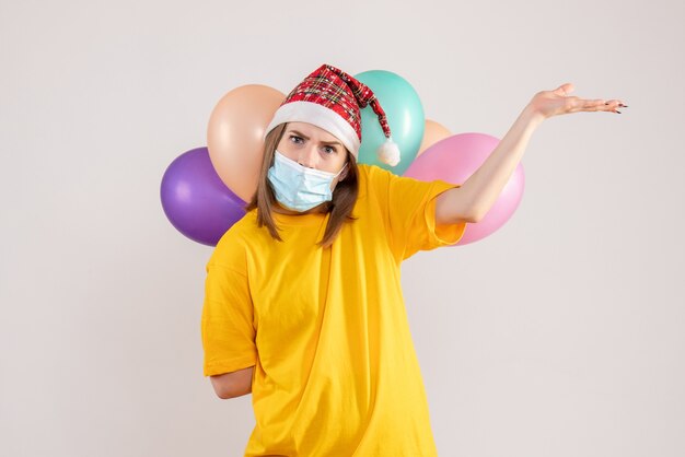 jonge vrouw met kleurrijke ballonnen in masker op wit