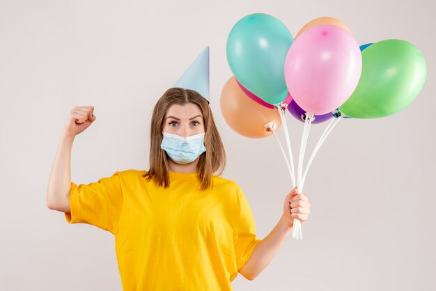 jonge vrouw met kleurrijke ballonnen in masker op wit