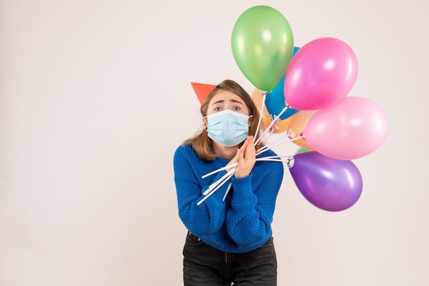 jonge vrouw met kleurrijke ballonnen in masker op wit