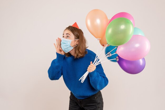 jonge vrouw met kleurrijke ballonnen in masker op wit