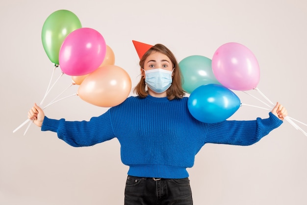 jonge vrouw met kleurrijke ballonnen in masker op wit