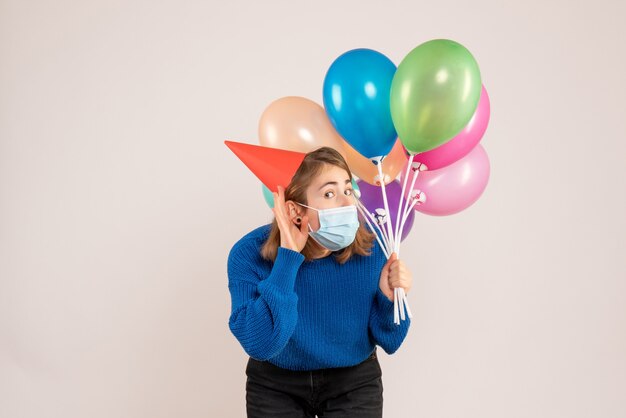 jonge vrouw met kleurrijke ballonnen in masker op wit