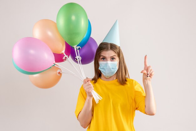 jonge vrouw met kleurrijke ballonnen in steriel masker op wit