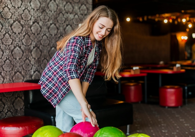 Jonge vrouw met kleurrijke bowlingballen