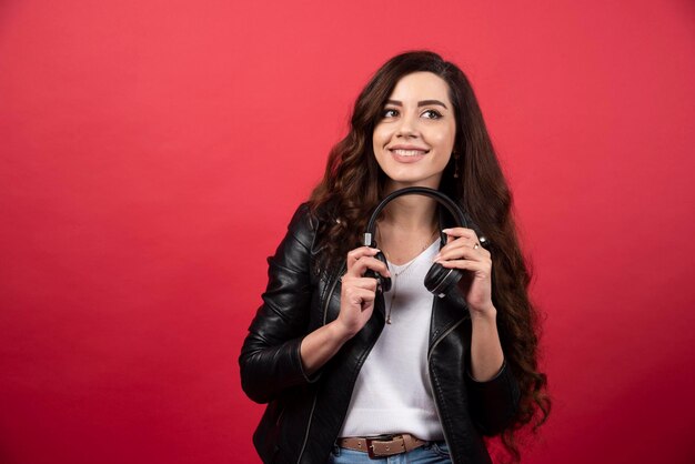 Jonge vrouw met koptelefoon en poseren op een rode achtergrond. Hoge kwaliteit foto