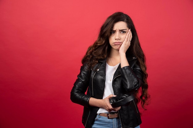 Jonge vrouw met koptelefoon en poseren op een rode achtergrond. Hoge kwaliteit foto