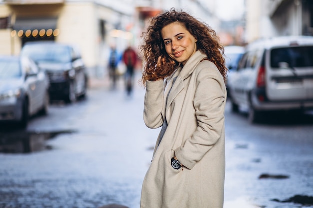 Jonge vrouw met krullend haar buiten de straat