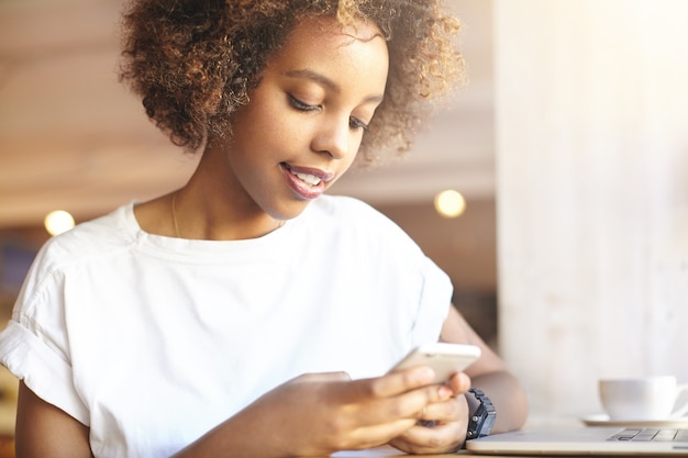 Jonge vrouw met krullend haar die telefoon met behulp van