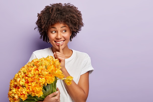 Jonge vrouw met krullend haar met boeket gele bloemen