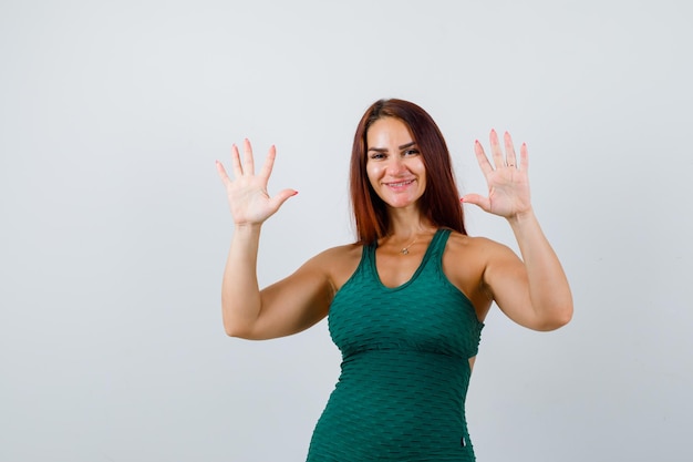 Gratis foto jonge vrouw met lang haar in een groene bodycon