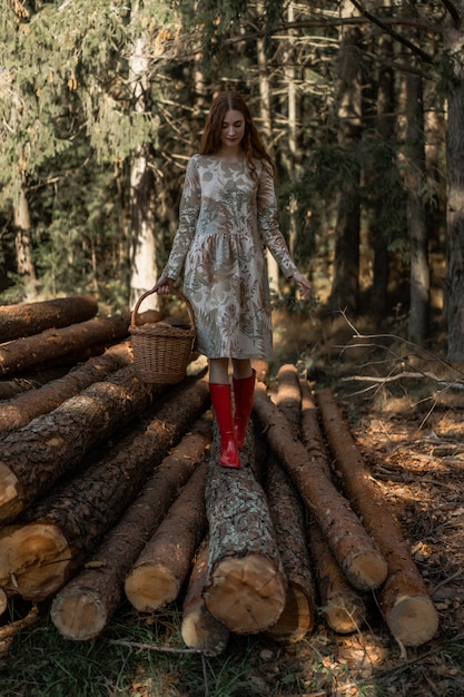 Jonge vrouw met lang rood haar in een linnenkleding die paddestoelen in het bos verzamelen