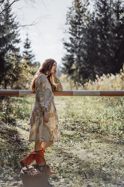 Jonge vrouw met lang rood haar in een linnenkleding die paddestoelen in het bos verzamelen