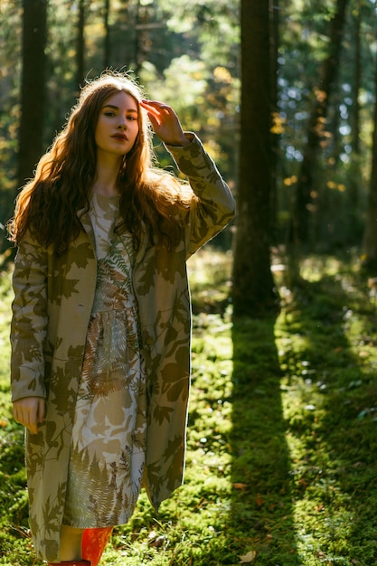 Jonge vrouw met lang rood haar in een linnenkleding die paddestoelen in het bos verzamelen