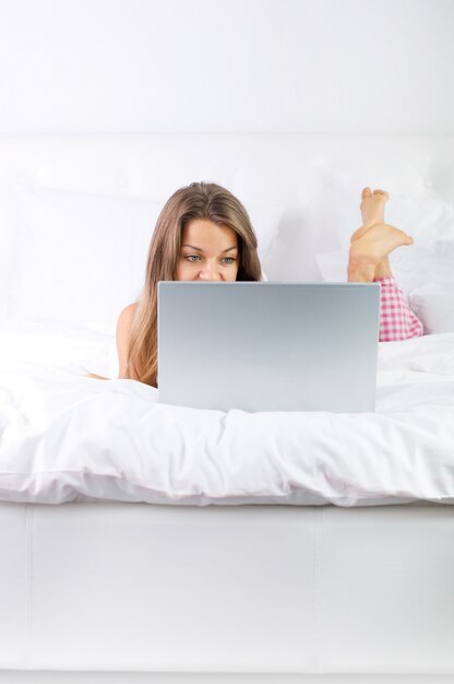 Jonge vrouw met laptop in bed