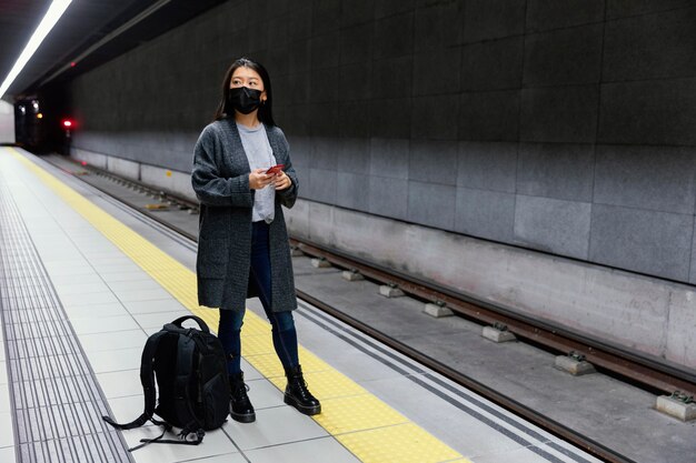 Jonge vrouw met masker bij metrostation