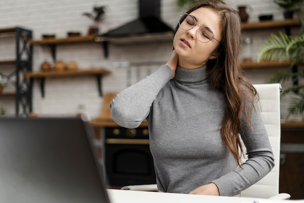 Jonge vrouw met nekpijn tijdens het werken vanuit huis