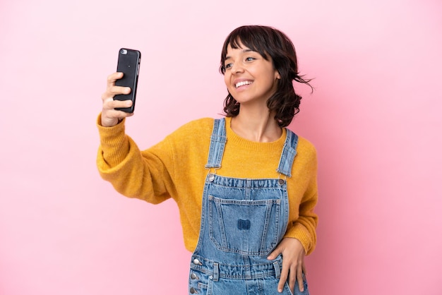 Jonge vrouw met overall geïsoleerde achtergrond die een selfie maakt