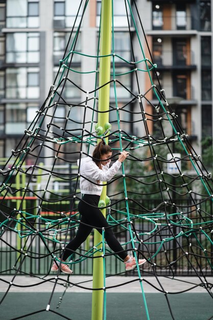 Jonge vrouw met plezier op de touwpiramide