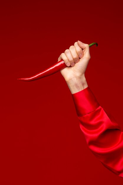 Jonge vrouw met rode chilipeper als mes