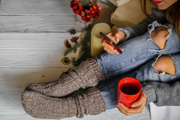 Jonge vrouw met rode kopje thee op haar slaapkamer