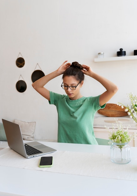 Gratis foto jonge vrouw met rommelig broodje thuiswerkend